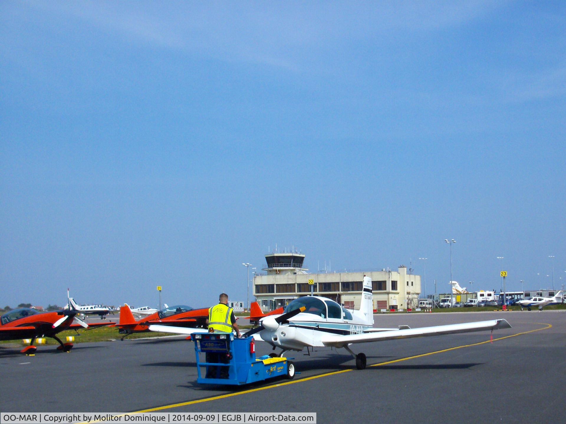 OO-MAR, 1973 Grumman American AA-5 Traveler C/N AA5-0424, Unusual sight on Guernsey Airport apron.OOMAR was being towed by the local ground handling staff shortly after its landing. In the background the UK aerobatic Team 