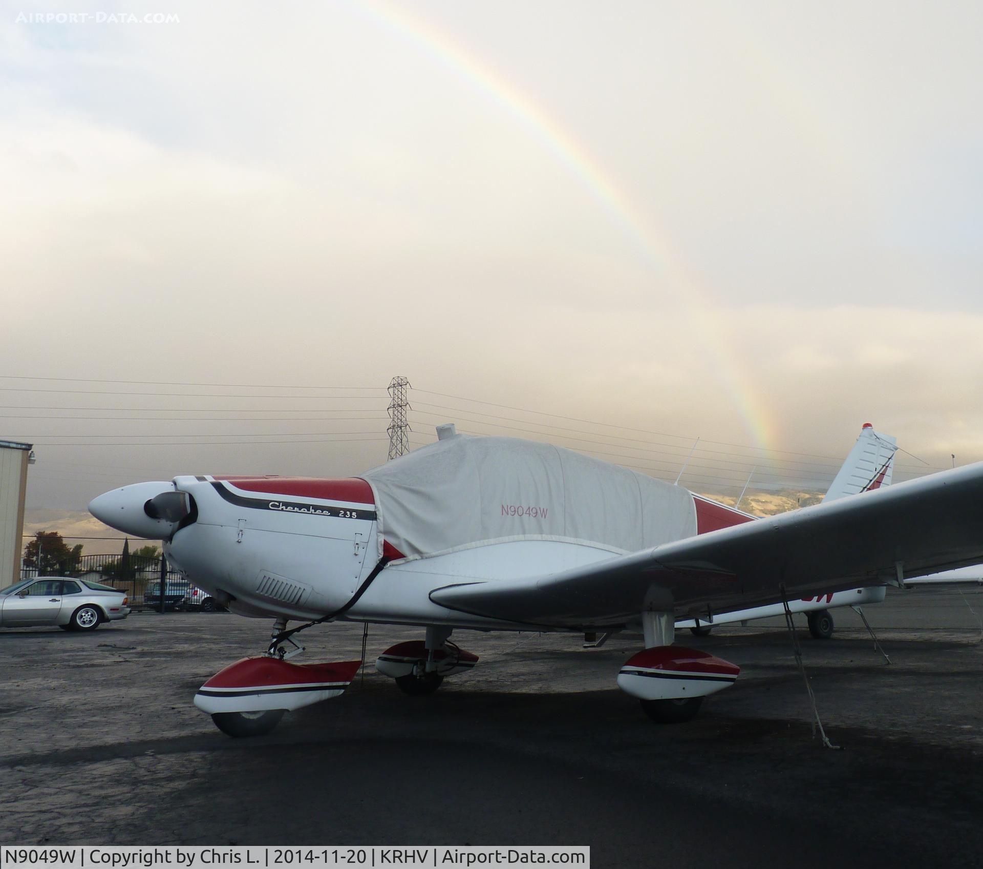 N9049W, 1965 Piper PA-28-235 Cherokee C/N 28-10643, A long time local Piper Cherokee sits next to the Laffery Aircraft Sales hangar just after an afternoon rain shower at Reid Hillview. Beautiful rainbow in the background!