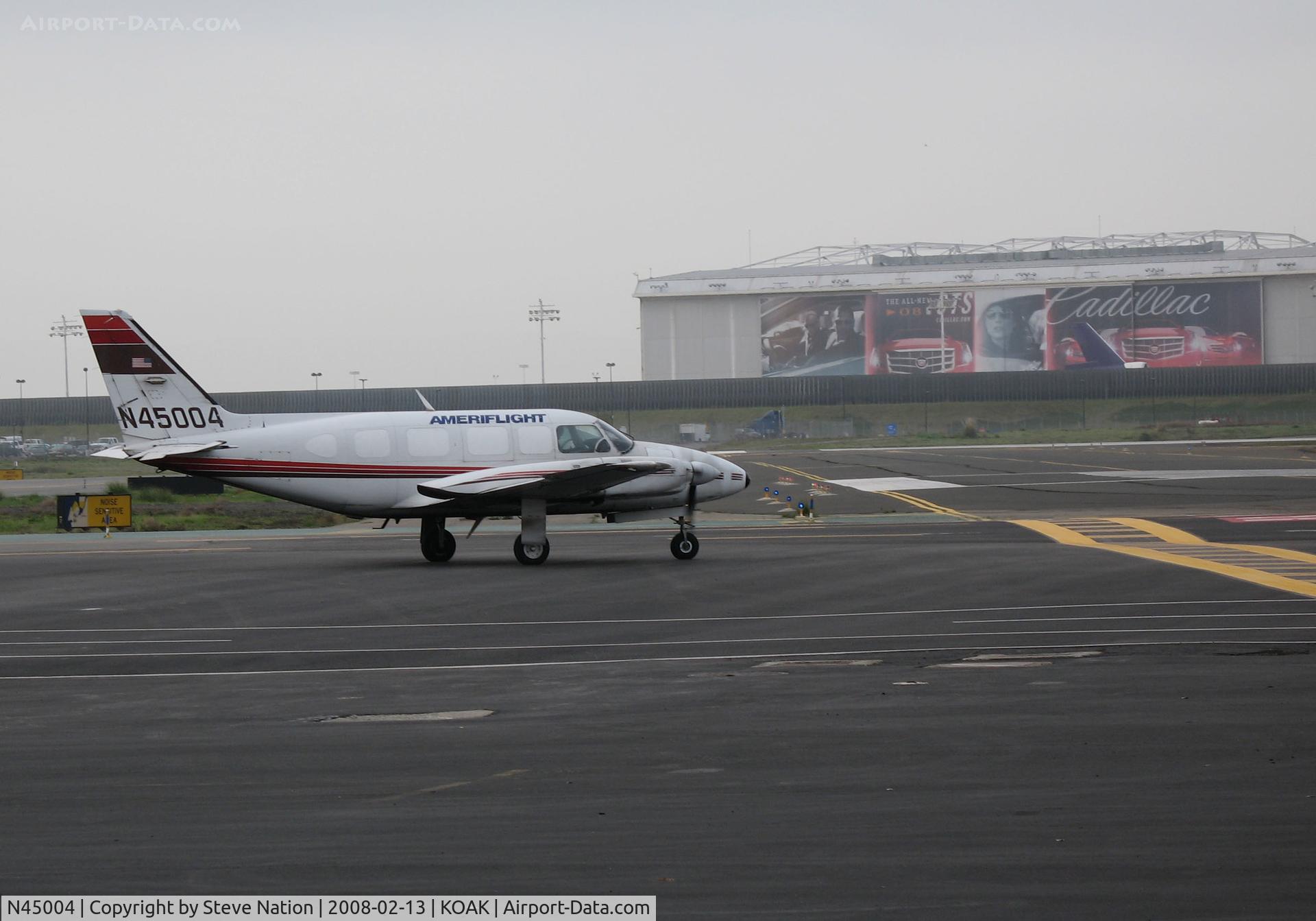 N45004, 1980 Piper PA-31-350 Chieftain C/N 31-8052163, Ameriflight 1980 Piper PA-31-350 ready to roll from Oakland Int'l North Ramp for a busy day collecting freight and mail across Northern California - note Cadillac commercial on old UA hangar across field