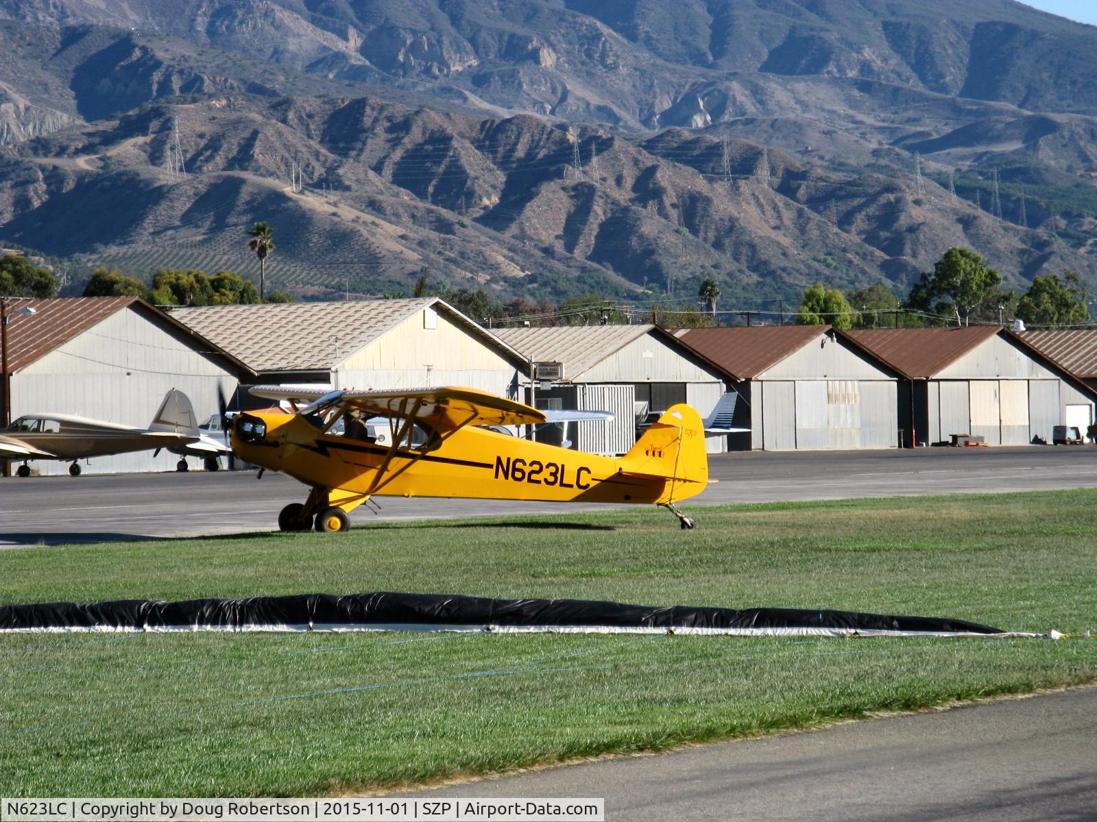 N623LC, 2006 American Legend AL3C-100 C/N AL-1024, 2006 American Legend Aircraft AL3C-100 CUB, Continental O-200 100 Hp open lower cowl version S-LSA, taxi off Rwy 22L grass after  STOL landing. Unrelated tow banner on grass in foreground.