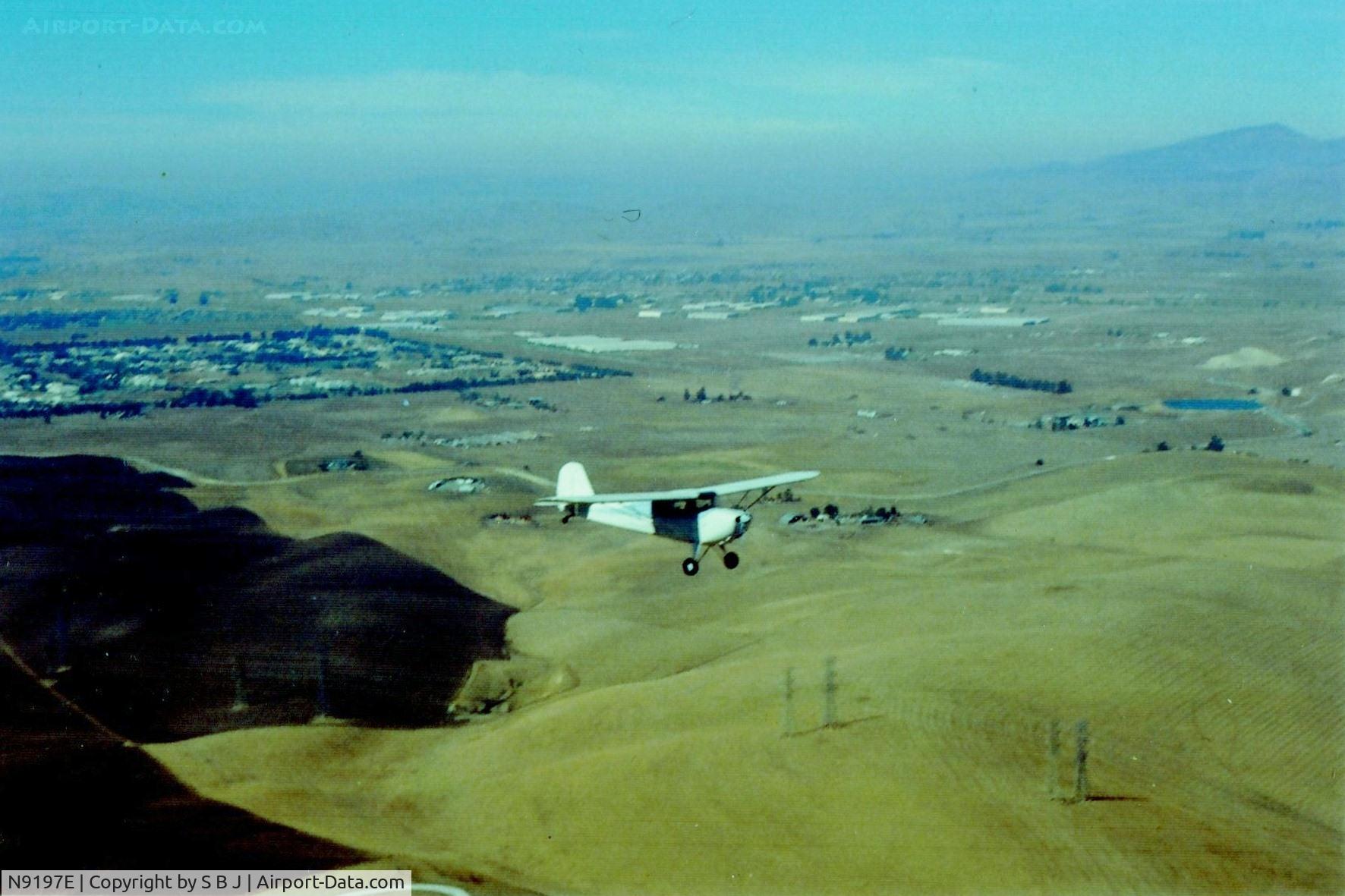N9197E, 1946 Aeronca 11AC Chief C/N 11AC-831, 97E near Livermore,Ca flying east to Tracy by its then owner,Ms Patty Gomez.This was around 1988.Behind 97E (tree lined area) was once Livermore Naval Air Station were 100s of WWII planes once flew.