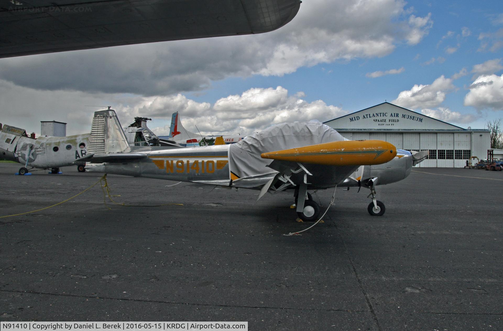 N91410, 1946 North American Navion (NA-145) C/N NAV-4-73, Still gleaming in her natural metal finish, this early Navion is part of the Mid Atlantic Air Museum, where she is taking refuge under the large wing of a Fairchild C-119 Flying Boxcar.