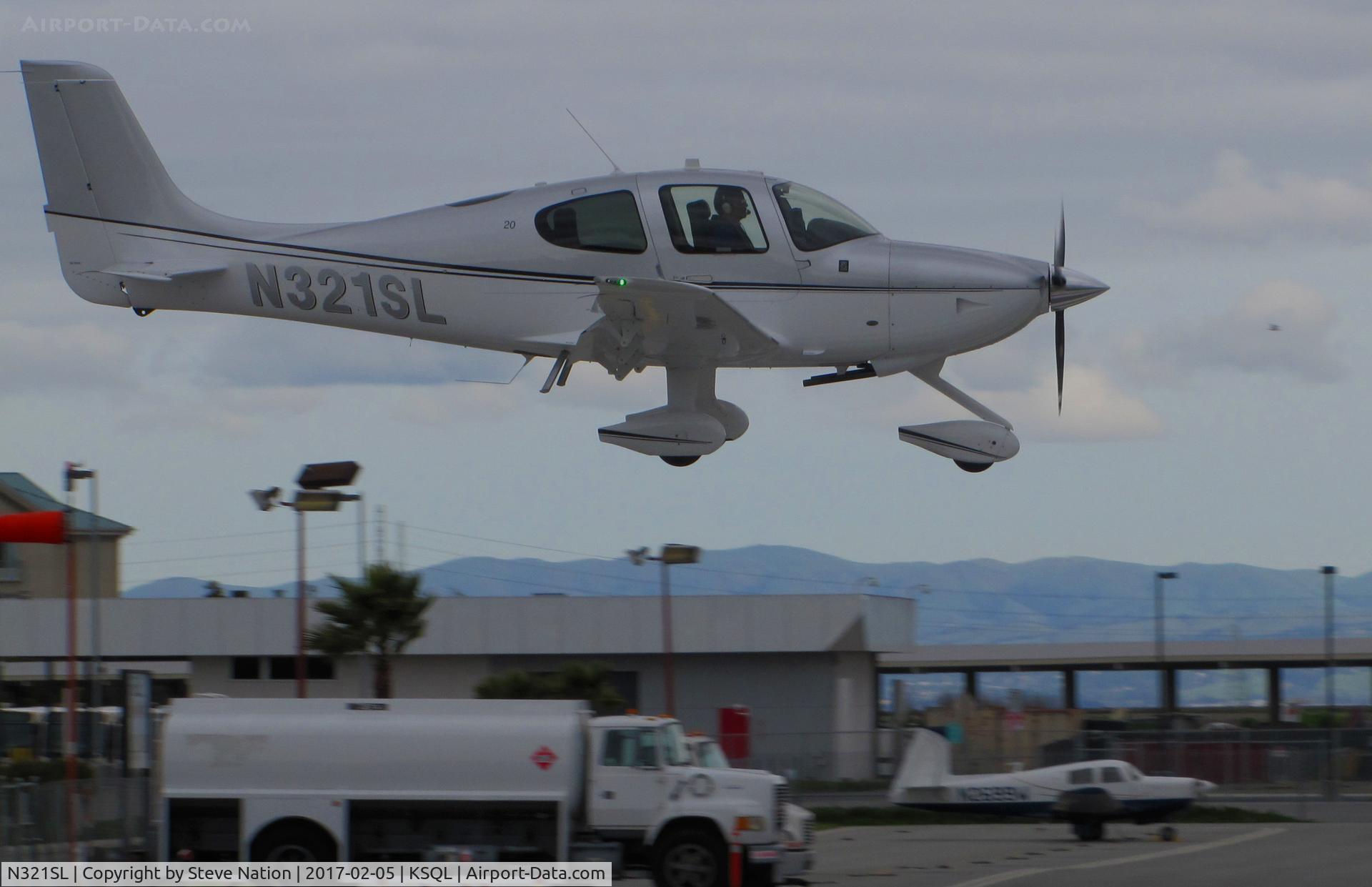 N321SL, 2016 Cirrus SR20 C/N 2325, Locally-based 2016 Cirrus SR20 over the threshold on raining morning @ San Carlos Airport, CA