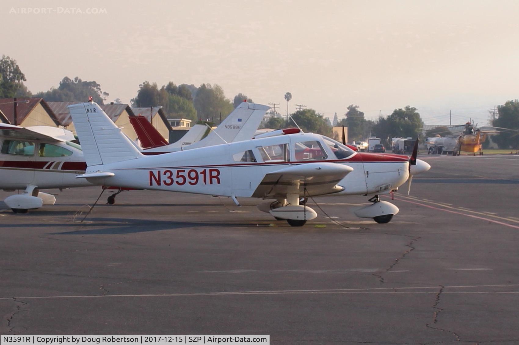 N3591R, 1970 Piper PA-28-180 Cherokee C/N 28-5704, 1970 Piper PA-28-180 CHEROKEE, Lycoming O&VO-360 180 Hp, on Transient ramp during the Thomas fire, note fire fighting helicopter in distance on Rwy 22 and smoky sky.