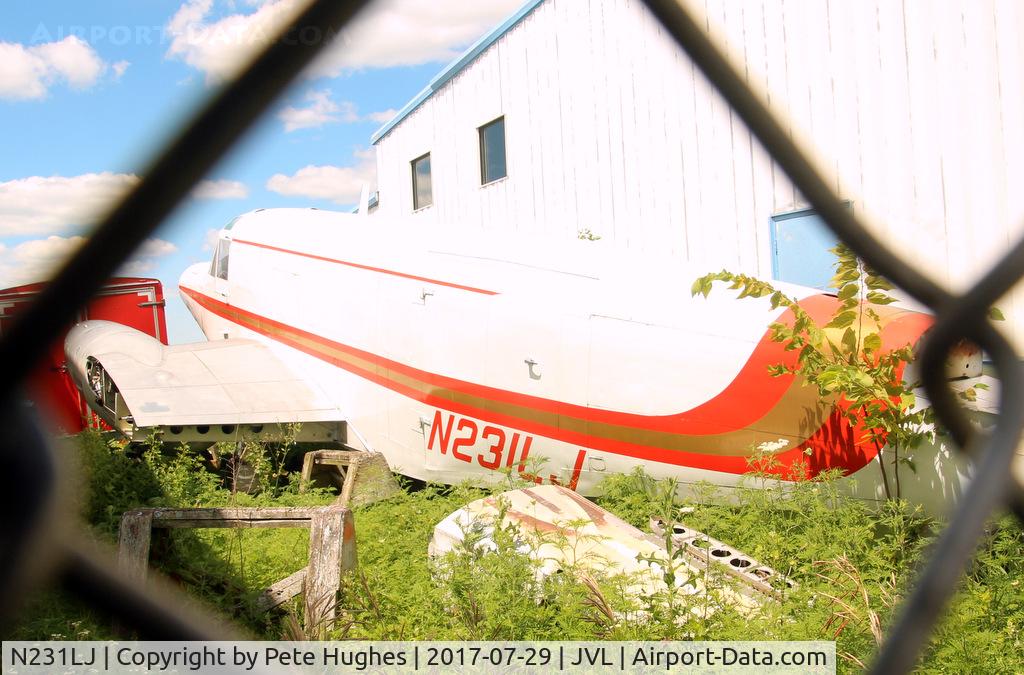 N231LJ, 1945 Beech TC-45J C/N 23835, N231LJ - much modified Beech 18 viewed in the grass through the fence between hangars where it soldiers on at Janesville, Southern Wisconsin