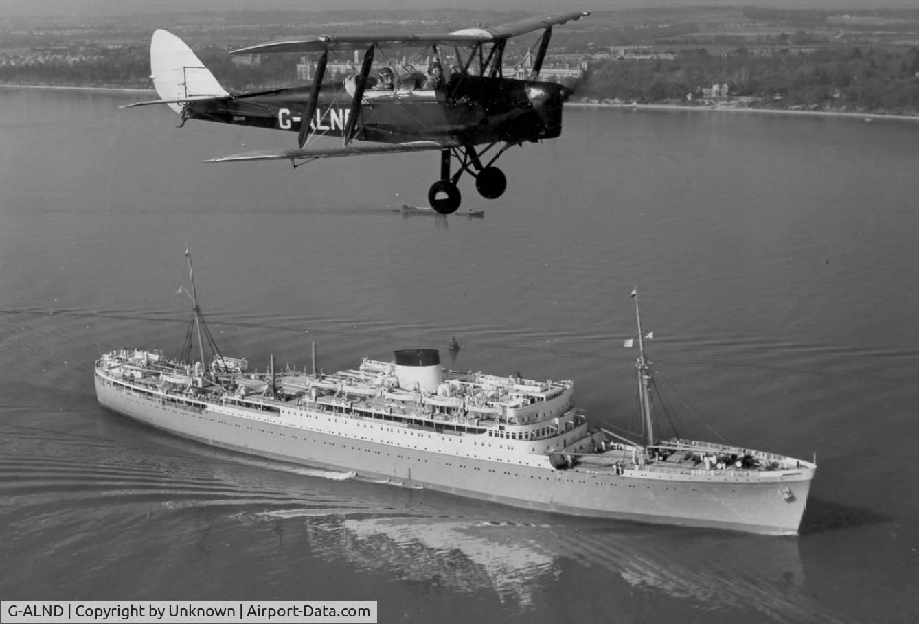 G-ALND, 1939 De Havilland DH-82A Tiger Moth II C/N 82308, Presumably based at the Hamble AFS. Picture taken prior to 1962 over Southampton Water with the Union-Castle liner Durban Castle below
