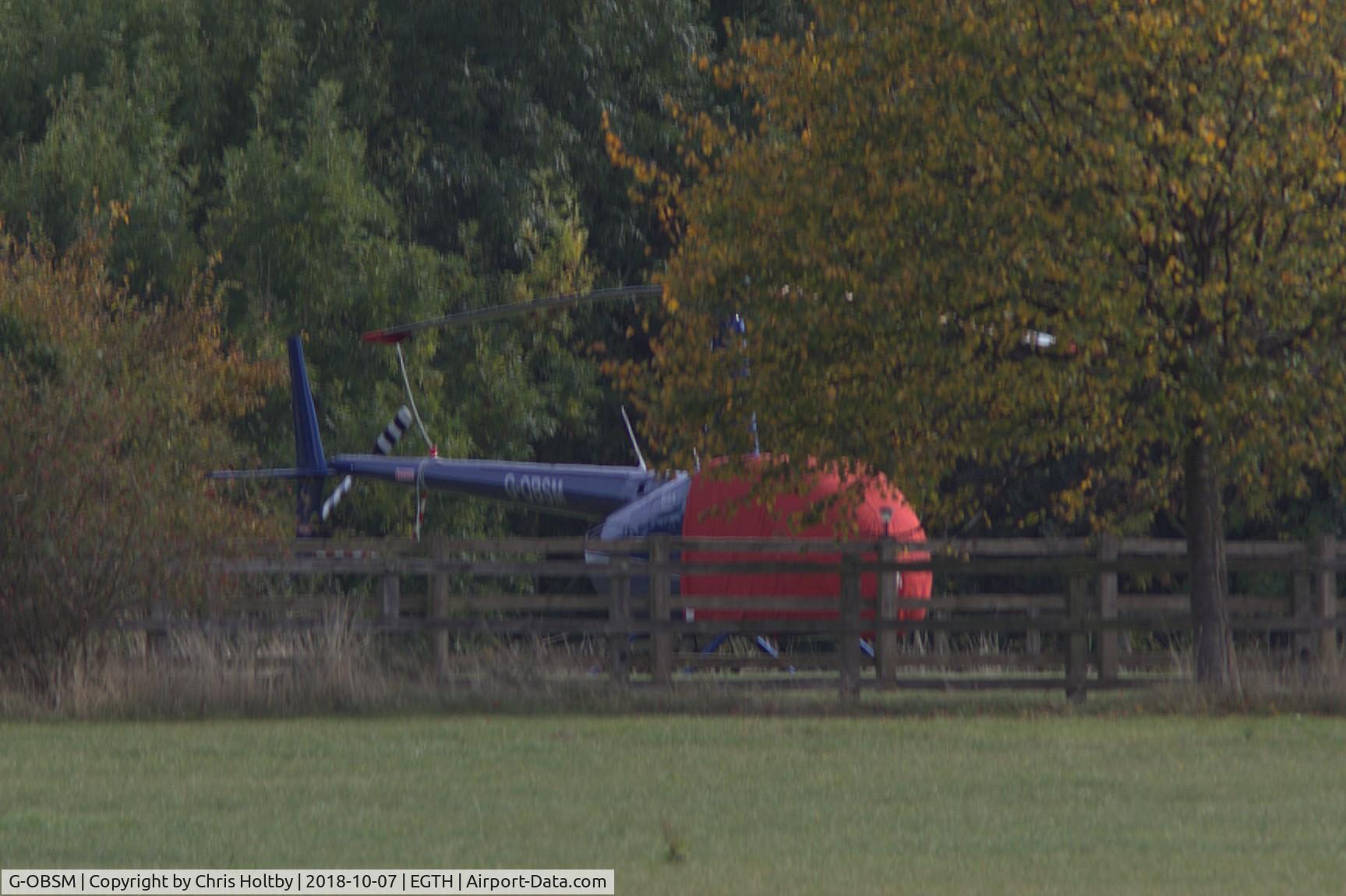 G-OBSM, 2001 Robinson R44 Raven C/N 1030, Parked and covered in private garden neighbouring Old Warden airfield on far side of main runway. Note change of livery.