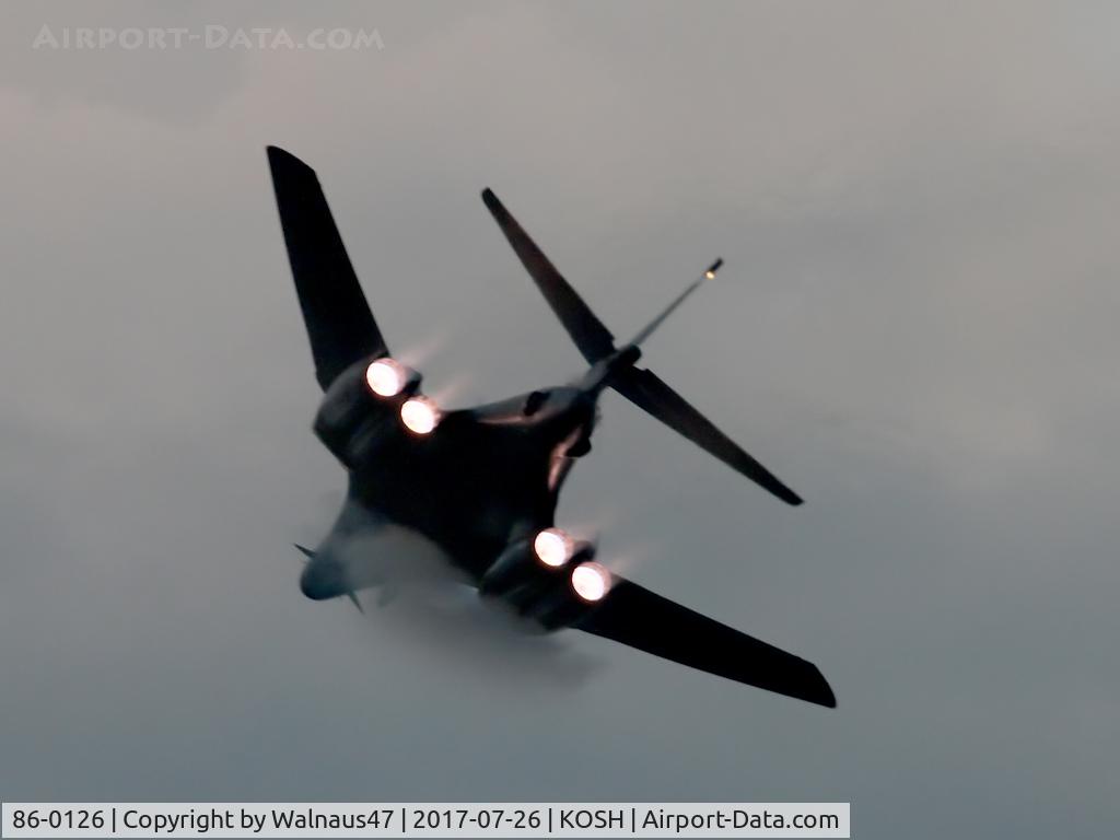 86-0126, 1986 Rockwell B-1B Lancer C/N 86, Low res Rear view of USAF B-1B AF 86-0126 Cn 86 starting a Dusk ‘Afterburner Vapour Run’, with wings sweeping back. Photo taken at the start of the Night Airshow, at Air Venture Oshkosh KOSH on 26Jul2017. Vapour forms as the aircraft punches into cloud.