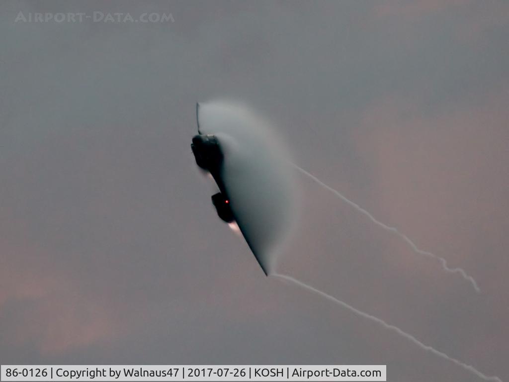 86-0126, 1986 Rockwell B-1B Lancer C/N 86, Low res front view of USAF B-1B AF 86-0126 Cn 86 starting a Dusk ‘Afterburner Vapour Run’, with wings swept back. Photo taken at the start of the Night Airshow, at Air Venture Oshkosh KOSH on 26Jul2017. Vapour blooms on the wings with the B-1B at Mach 1.