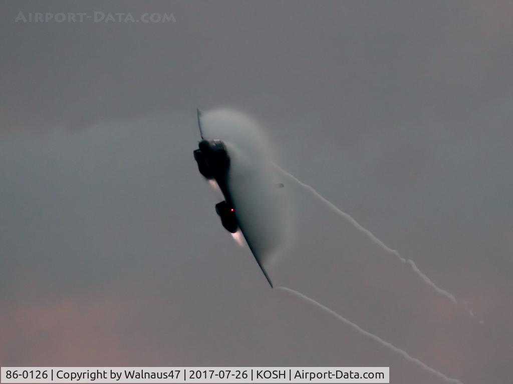 86-0126, 1986 Rockwell B-1B Lancer C/N 86, Low res front view of USAF B-1B AF 86-0126 Cn 86 starting a Dusk ‘Afterburner Vapour Run’, with wings swept back. Photo taken at the start of the Night Airshow, at Air Venture Oshkosh KOSH on 26Jul2017. Vapour blooms on the wings with the B-One at Mach 1.