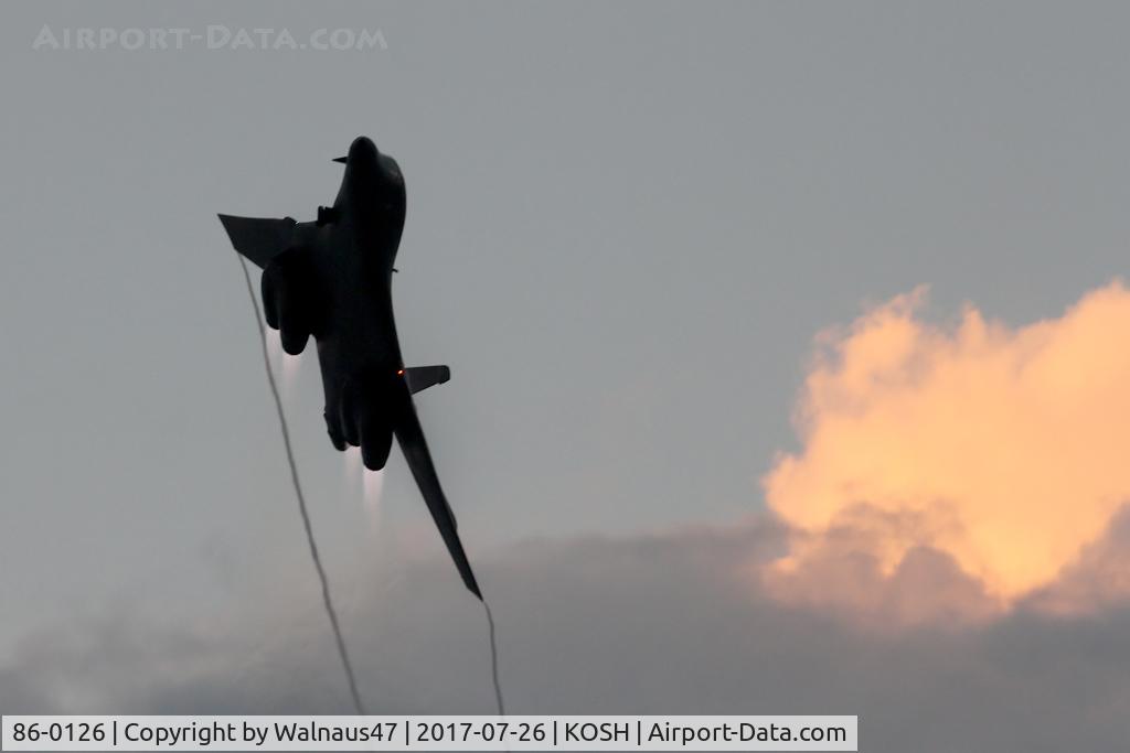 86-0126, 1986 Rockwell B-1B Lancer C/N 86, Front view of USAF B-1B AF 86-0126 Cn 86 breaking clear after a Dusk ‘Afterburner Vapour Run’. Photo taken at the start of the Night Airshow, at Air Venture Oshkosh on 26Jul2017. The B-1 is streaming vapour from the  wingtips while passing a sunlit Cu-Nim