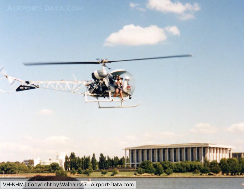 VH-KHM, 1967 Bell 47G-3B-1 Sioux C/N 6629, Heli-Muster Bell 47G-3B-1 helicopter VH-KHM Cn 6629  hovering at Canberra’s Lake Burley Griffin in Mar 1991. (The National Library is visible at rear.) The helo was in town for Canberra Week activities.