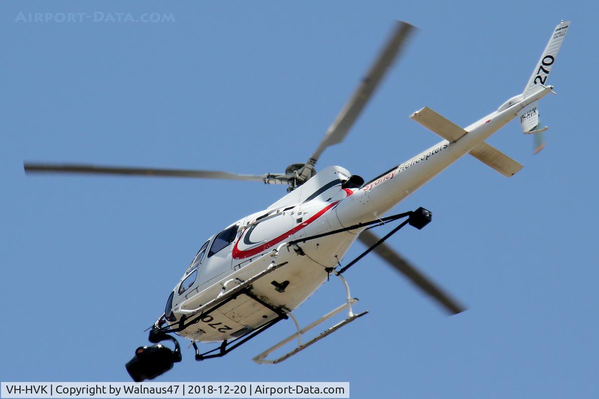 VH-HVK, 1985 Eurocopter AS-350B Ecureuil Ecureuil C/N 1843, Sydney Helicopters Aerospatiale AS 350B Ecureuil VH-HVK Cn 1843 Code 270 flying low over southern Canberra suburbs on 20Dec2018. The helo has a ‘Video Sensor ball’ mounted under the nose, and has a ‘counter-balance’  mounted on struts behind the cabin.