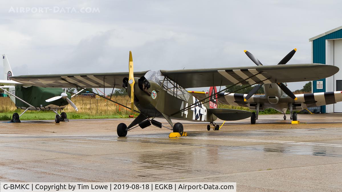 G-BMKC, 1943 Piper L-4H Grasshopper (J3C-65D) C/N 11145, Parked on the Heritage Hangar apron in a peak of sunlight with two seater Spitfire G-AVAV and the Airvan that takes people to fly alongside a Spitfire G-CSPT.
