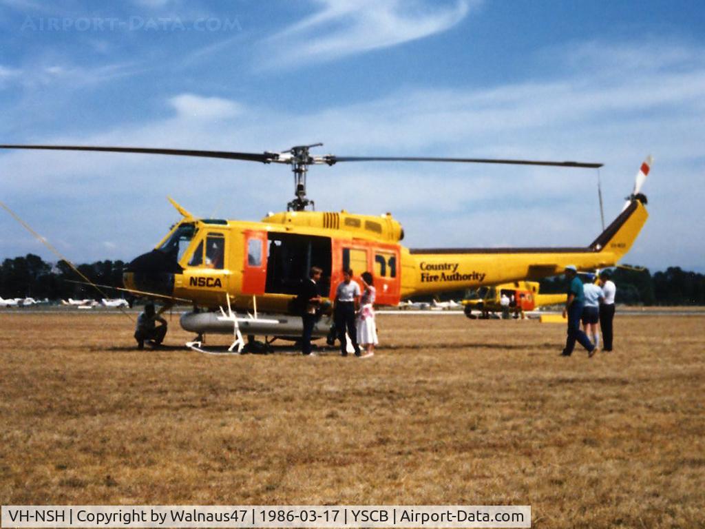 VH-NSH, 1975 Bell 205A-1 C/N 30195, Low res Port side view of parked NSCA Bell 205A-1 VH-NSH Cn 30195 Code 01 at Canberra Airport YSCB on 17Mar1986. This Helo is equipped with a water tank and filler hose, for Fire-fighting duties. Later Re-Regd as VH-NGK.