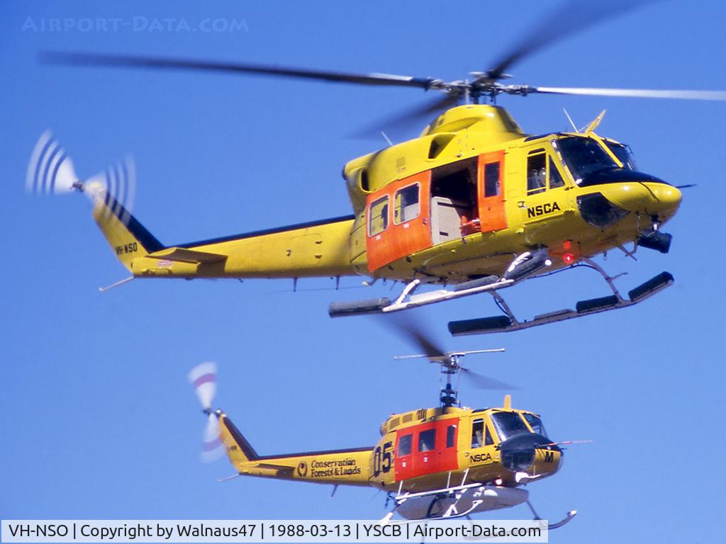 VH-NSO, 1998 Schempp-Hirth Discus 2b C/N 8, Two NSCA Helicopters (in High-Vis Yellow livery) hovering at the 1988 (Bi-Centennial) Canberra Air Pageant on 13Mar1988.  Bell 412 VH-NSO Cn 33089 Code 11, and Bell 205 VH-NSM Cn 30002 Code 05 is equipped with a water tank and filler hose.