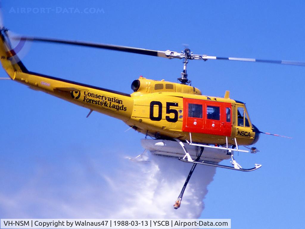 VH-NSM, 1968 Bell 205A-1 C/N 30002, NSCA Bell 205A-1 VH-NSM Cn 30002 Code 05 demonstrates a water dump at the 1988 (Bi-Centennial) Canberra Air Pageant on 13Mar1988. This Helo (wearing a 'Conservation - Forests and Lands' logo) is equipped with a water tank and filler hose, for Fire-fightin