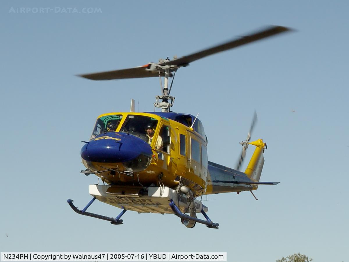 N234PH, 1977 Bell 214B-1 Biglifter C/N 28050, Front Portside view of McDermott Aviation Bell 214B-1 Biglifter N234PH Cn 28050 hovering at Bundaberg Airshow at Bundaberg Airport YBUD on 16Jul2005. Equipped with ‘under-cabin’ water tank, with ‘pick-up’ hose retracted.