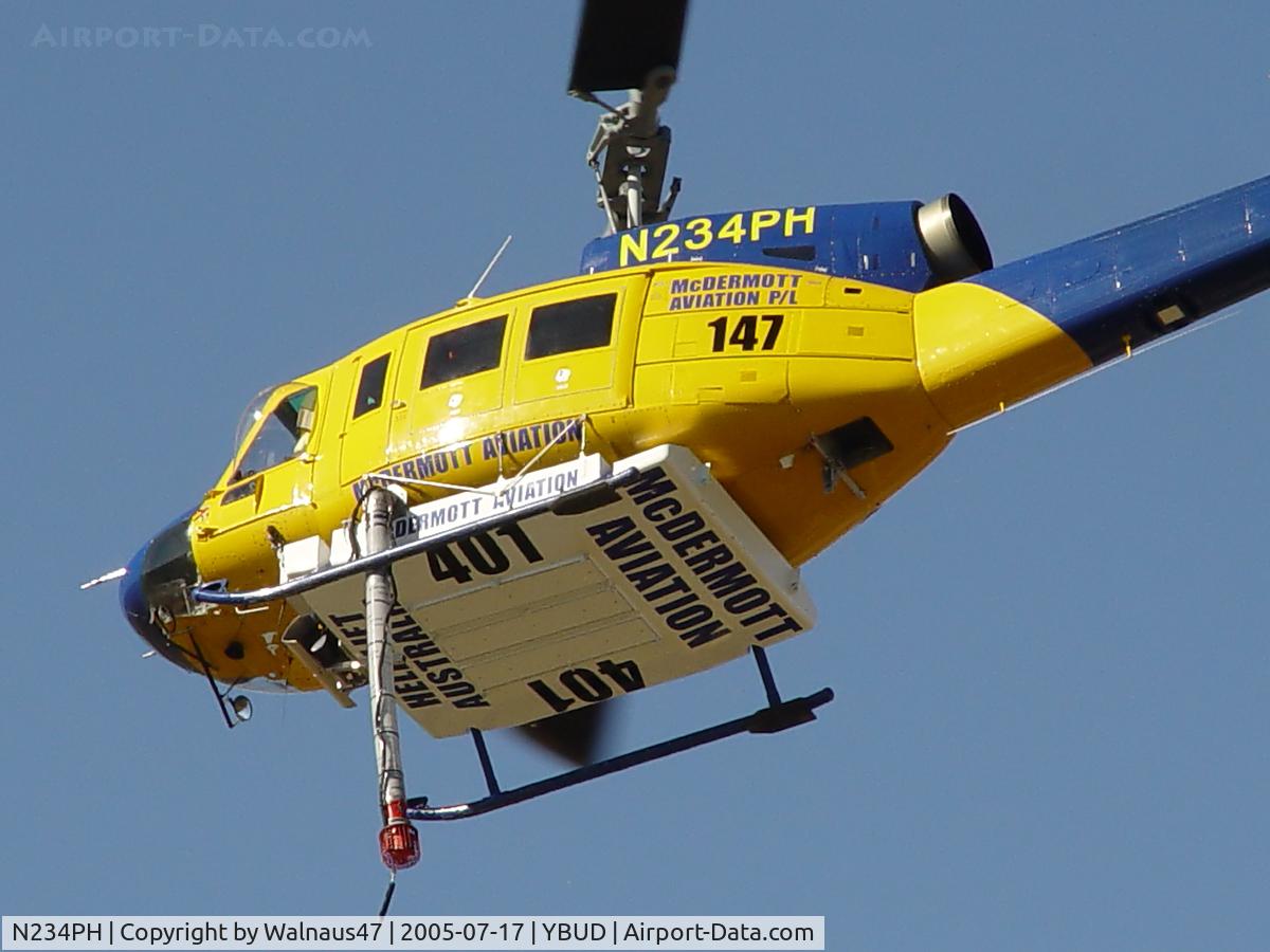 N234PH, 1977 Bell 214B-1 Biglifter C/N 28050, Rear Port underside view of front end of McDermott Aviation Bell 214B-1 Biglifter N234PH Cn 28050 hovering at Bundaberg Airshow at Bundaberg Airport YBUD on 17Jul2005. Equipped with ‘under-cabin’ water tank, with ‘pick-up’ hose extended.