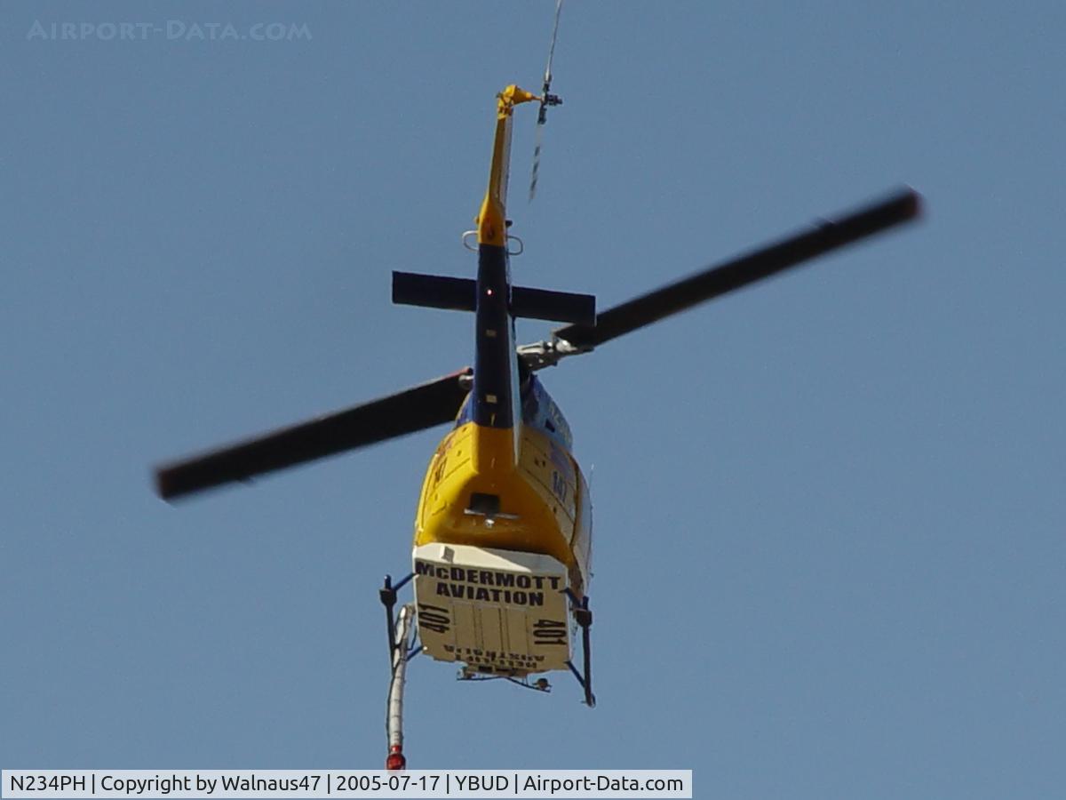 N234PH, 1977 Bell 214B-1 Biglifter C/N 28050, Rear underside view of McDermott Aviation Bell 214B-1 Biglifter N234PH Cn 28050 departing at Bundaberg Airshow at Bundaberg Airport YBUD on 17Jul2005. Equipped with ‘under-cabin’ water tank, with ‘pick-up’ hose extended.