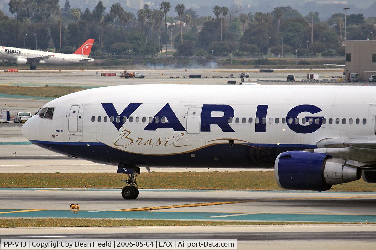 PP-VTJ, 1991 McDonnell Douglas MD-11 C/N 48455, Close-up of Varig PP-VTJ (FLT VRG8836) on taxiway Tango, about to cross RWY 25R after arrival on RWY 25L from Guarulhos Int'l (SBGR)-Sao Paulo, Brazil. In the background, Northwest Airlines (FLT NWA627) is arriving on RWY 24R from McCarran Int'l (KLAS).