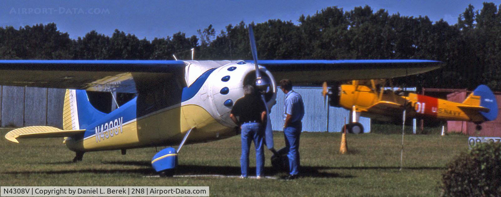 N4308V, 1948 Cessna 195 C/N 7215, A Boeing Stearman whizzes past while two pilots inspect this 1948-vintage Cessna 195.