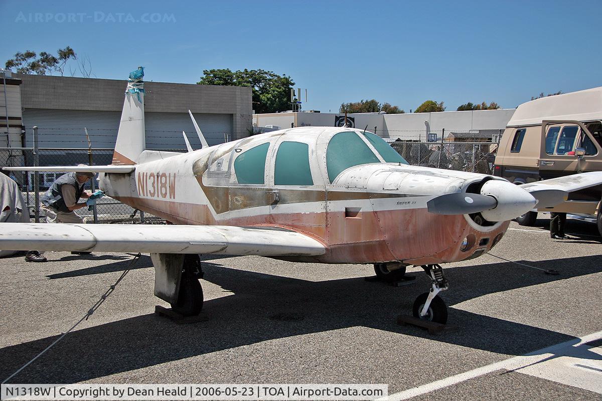 N1318W, 1963 Mooney M20E C/N 206, A weathered 1963 Mooney M20E Super 21 N1318W on the ramp at Torrance Municipal Airport (KTOA), CA.  A man is seen here working on the tail section of the aircraft.