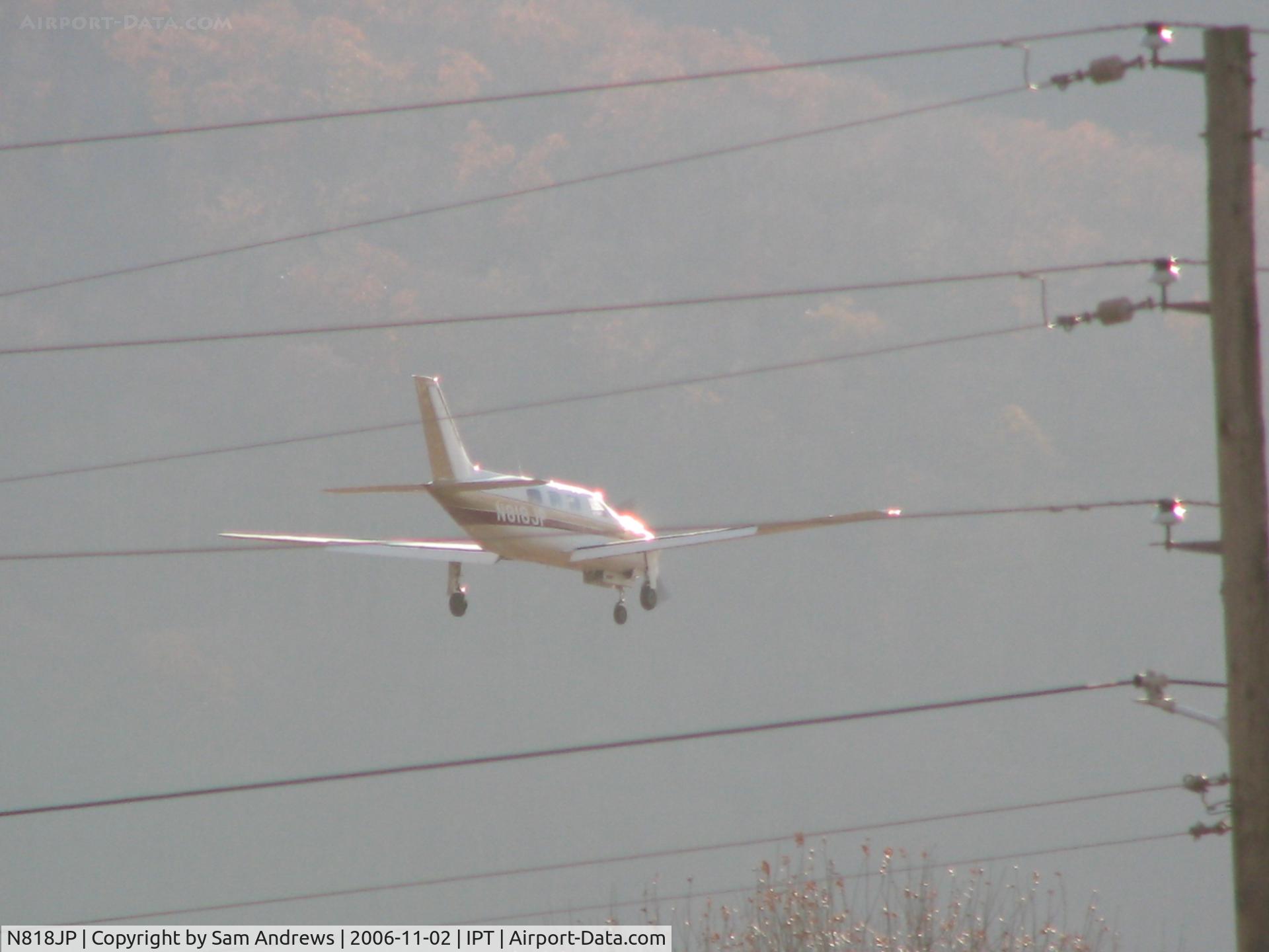 N818JP, 1984 Piper PA-46-310P Malibu C/N 46-8408047, Back lit and behind wires.  He is about 150' above the runway at this point.