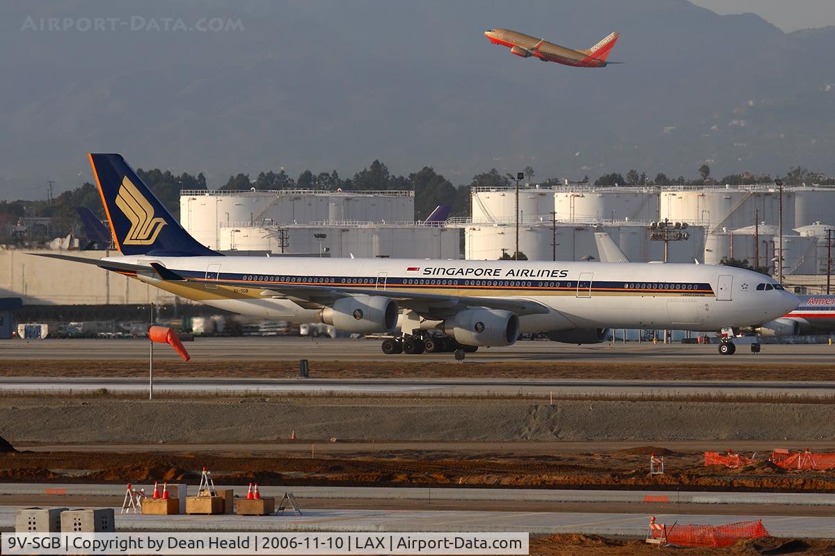9V-SGB, 2003 Airbus A340-541 C/N 499, Singapore Airlines 9V-SGB taxiing to the Tom Bradley International Terminal  after arrival on the north complex. Southwest FLT 2658 climbing out from RWY 24L enroute to Nashville can be seen in the background.