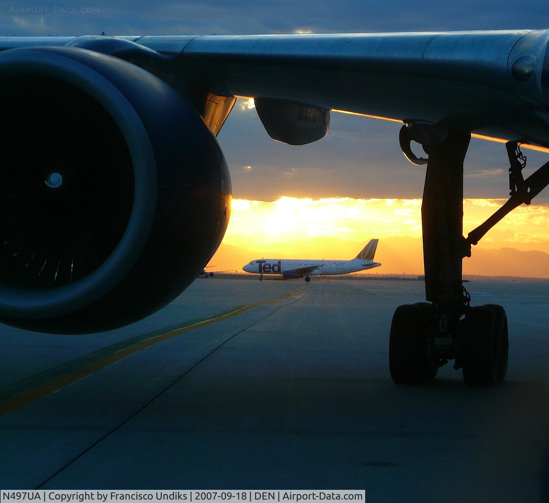 N497UA, 2002 Airbus A320-232 C/N 1847, Ted A320 framed by 757 landing gear.