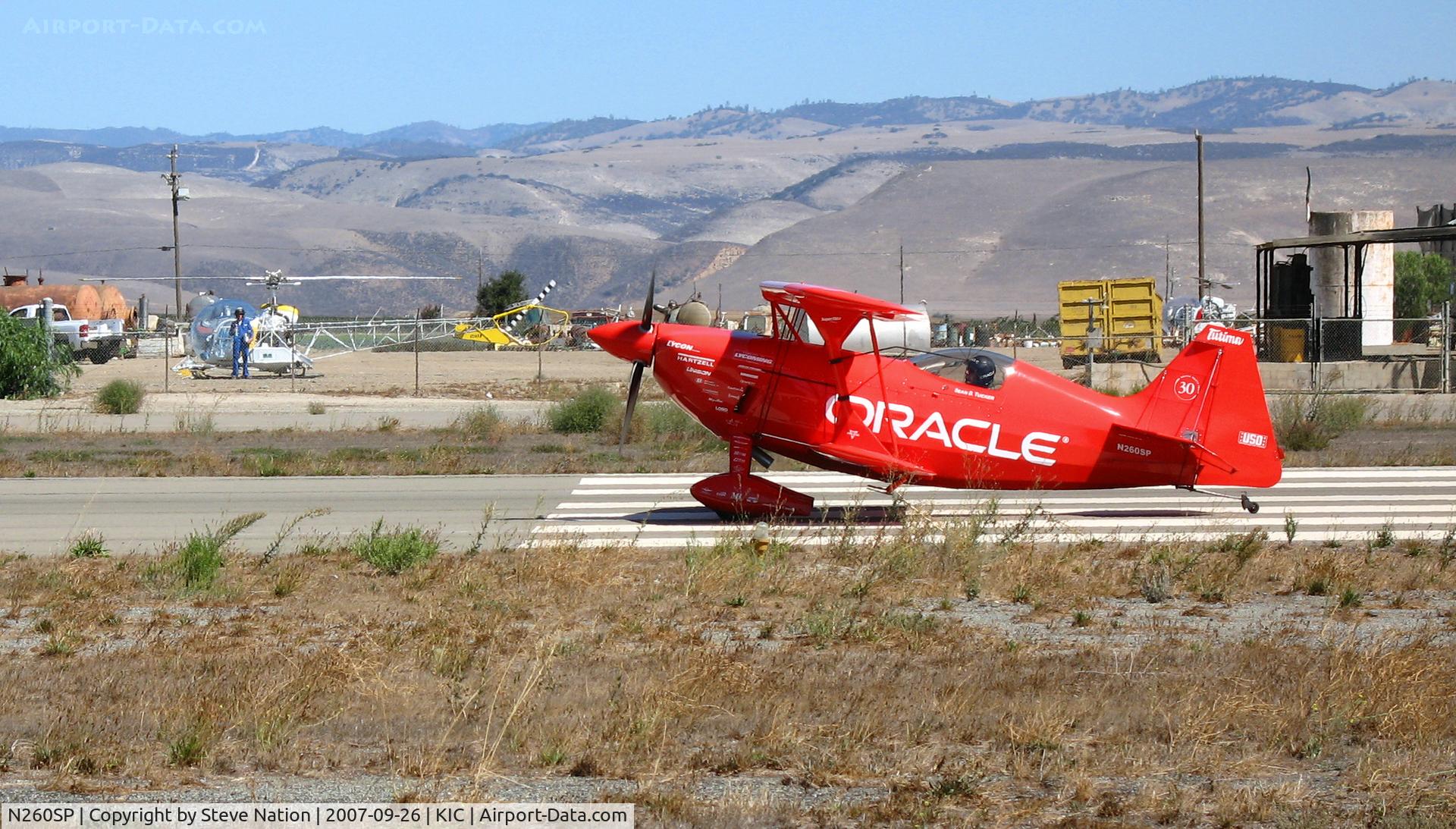 N260SP, 1981 Pitts S-2S Special C/N 1114C, Vibrantly-painted ORACLE/Tutima 1981 Oliver Steven R PITTS S-2S nginning take-off roll (note: SoilServ Bell 47G cropduster and pilot in background) @ Mesa Del rey (King City) Municipal Airport, CA