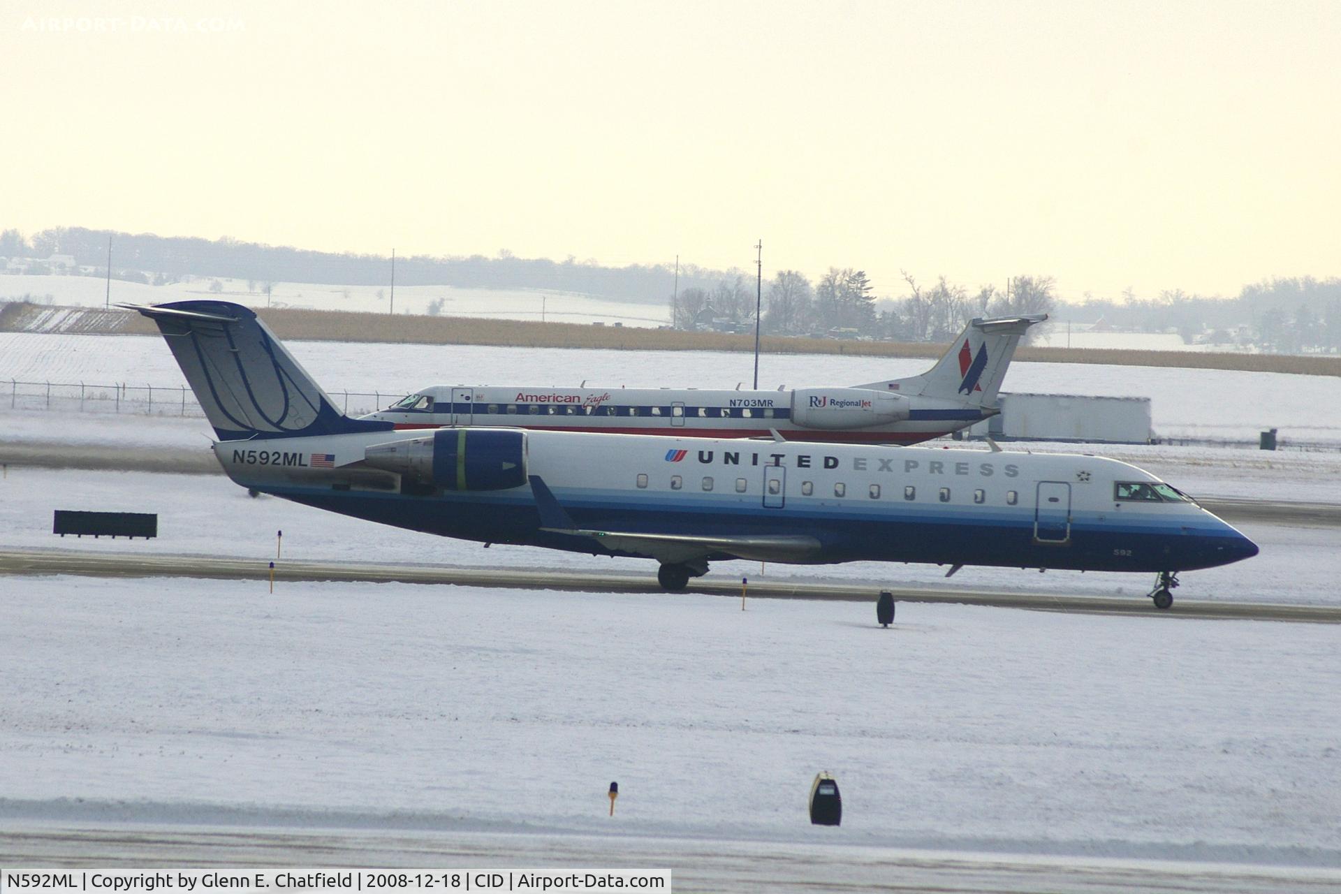 N592ML, 2000 Bombardier CRJ-200ER (CL-600-2B19) C/N 7410, Taxiing to Runway 9 for departure.  N703MR rolling out after landing in the background.