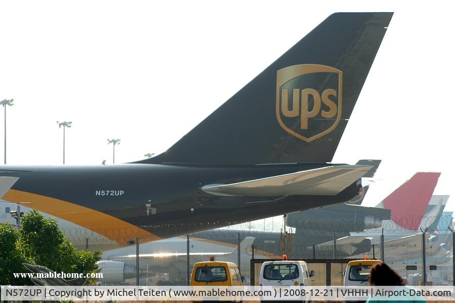 N572UP, 2007 Boeing 747-44AF C/N 35669, UPS waiting on the impressive flightline of the cargo area of Hong Kong, unfortunately hidden by fences
