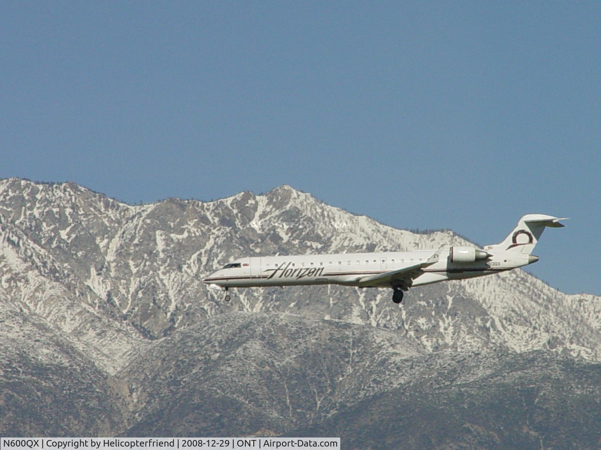 N600QX, 2001 Bombardier CRJ-701 (CL-600-2C10) Regional Jet C/N 10005, Passing snow covered mountains on final