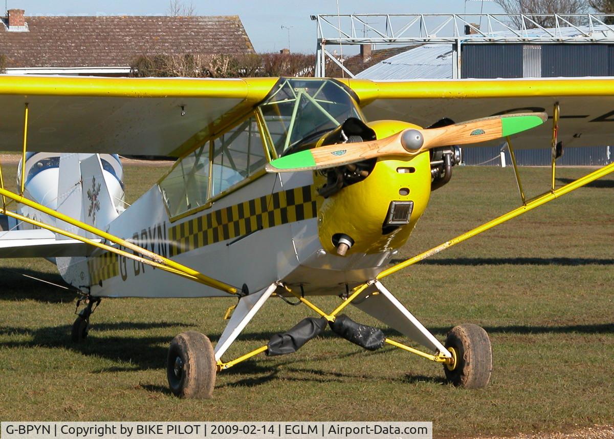 G-BPYN, 1943 Piper L-4H Grasshopper (J3C-65D) C/N 11422, COLORFUL PIPER OUTSIDE ONE OF THE MAINTENANCE HANGERS