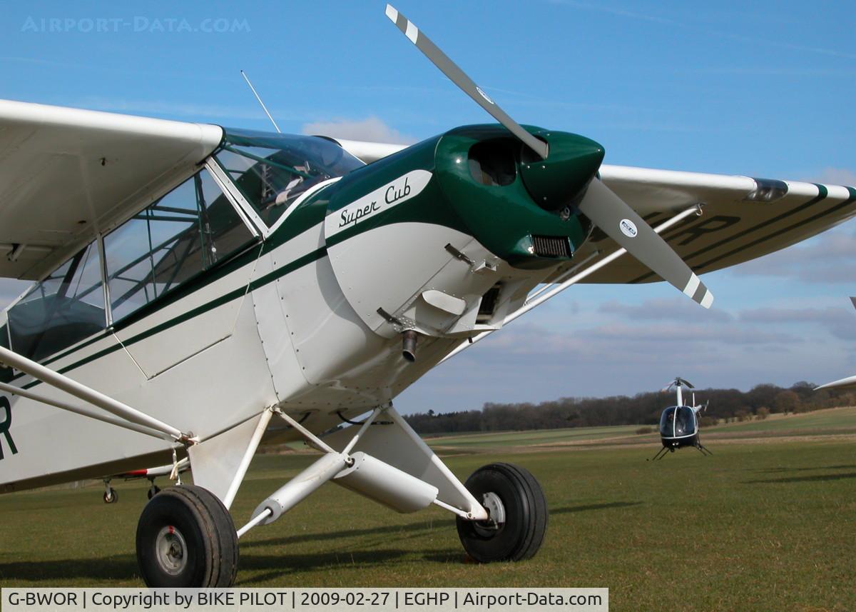 G-BWOR, 1952 Piper L-21B Super Cub C/N 18-2547, SITTING IN THE SUN WITH AN R22 BEHIND