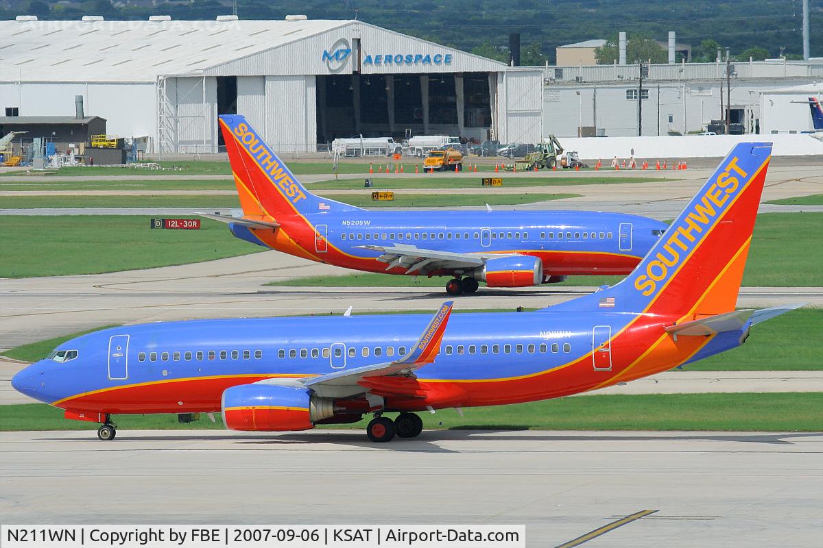 N211WN, 2005 Boeing 737-7H4 C/N 34163, Southwest B737 taxies to the holding point, while another reduces speed on the runway