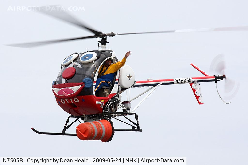 N7505B, 1985 Schweizer 300C (269C) C/N S1205, Roger Buis, a retired Army Master Aviator with more than 16,500 flight hours waves to the crowd while piloting Otto the Helicopter with a plastic barrel on the left skid.