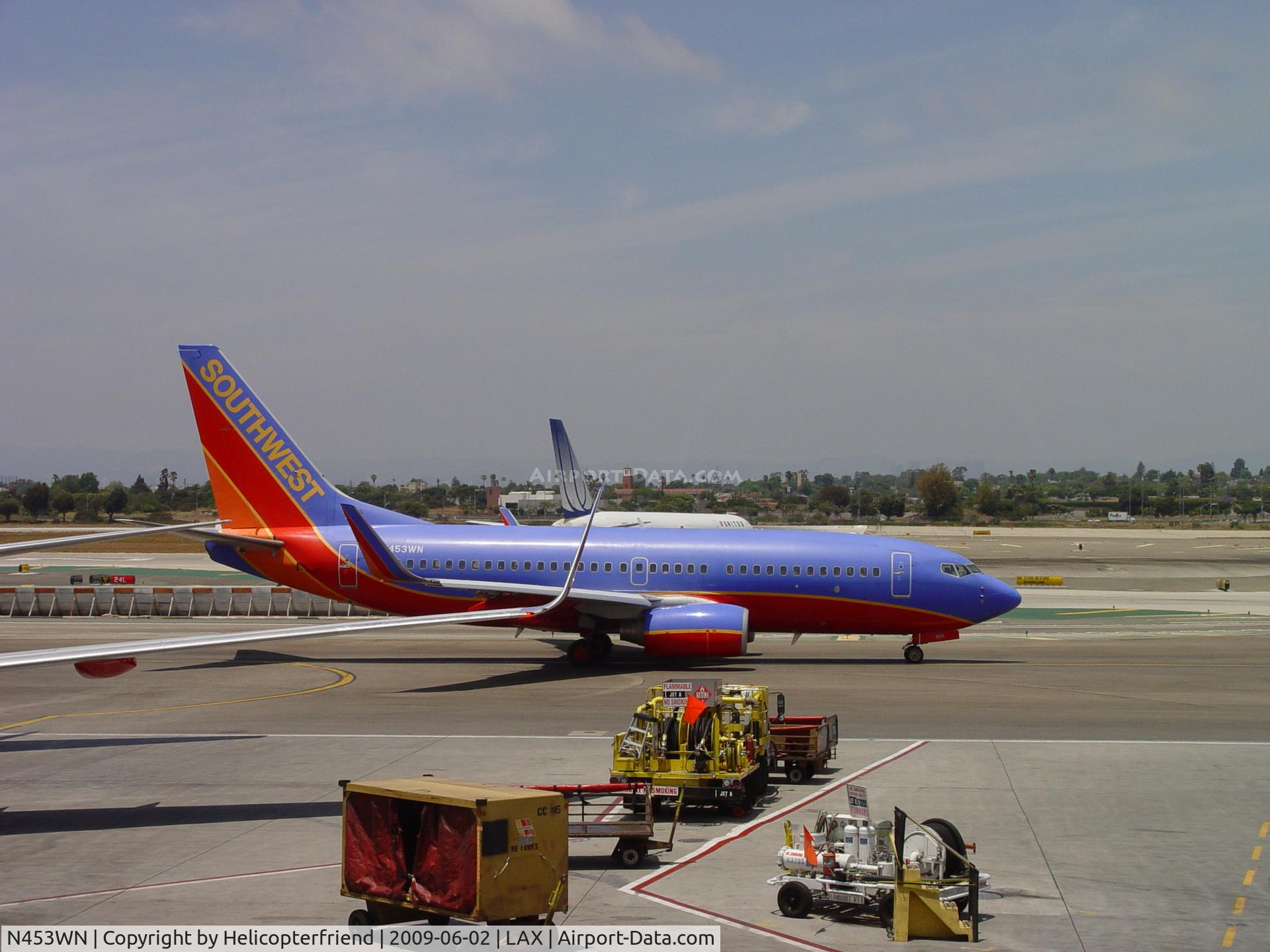N453WN, 2004 Boeing 737-7H4 C/N 29847, Taxiing past N598UA and waiting to take off on Ruway 24L