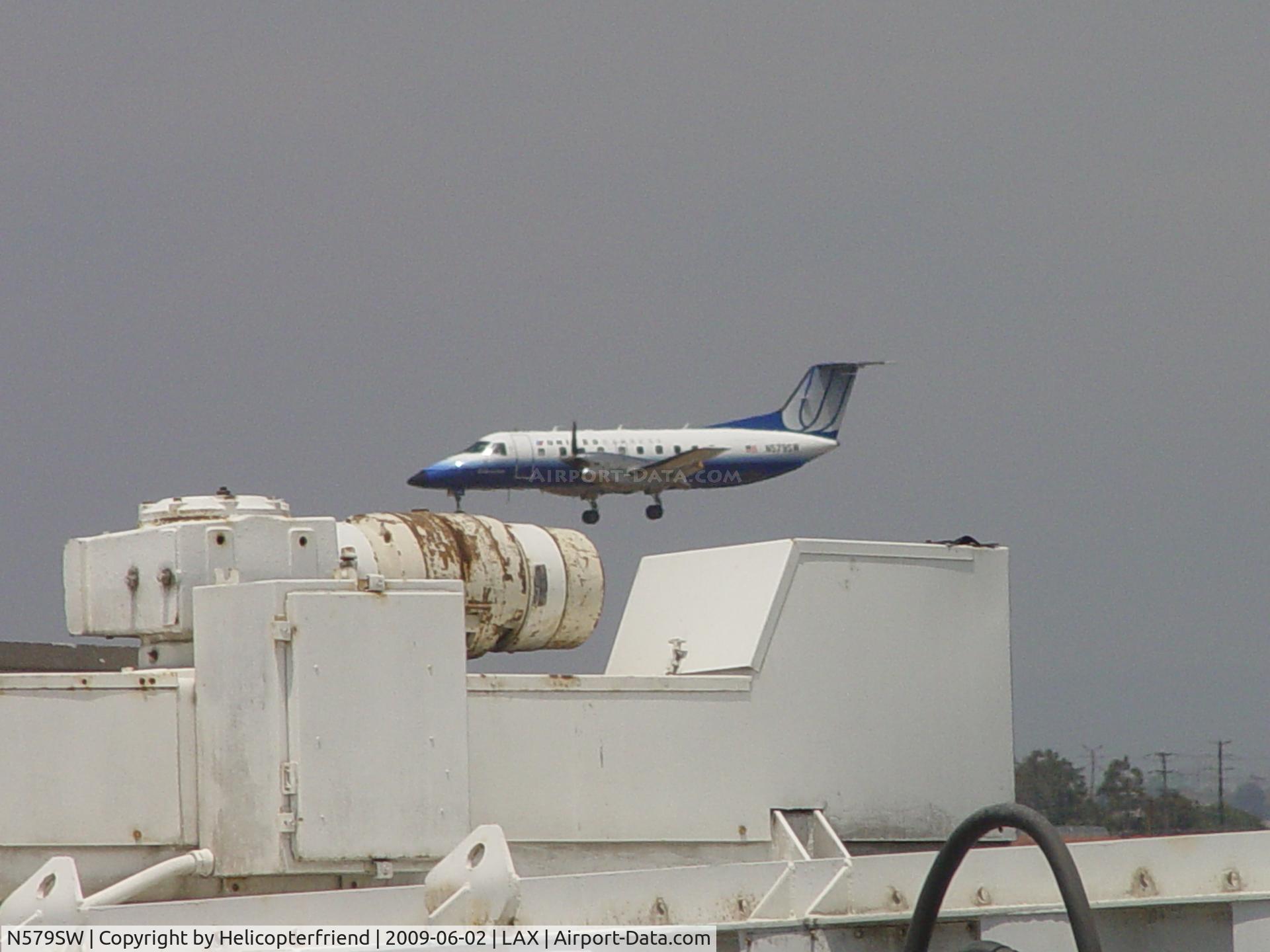 N579SW, 1998 Embraer EMB-120ER Brasilia C/N 120347, Inbound for Runway 24R shot over Gate 13 passenger walkway machinery