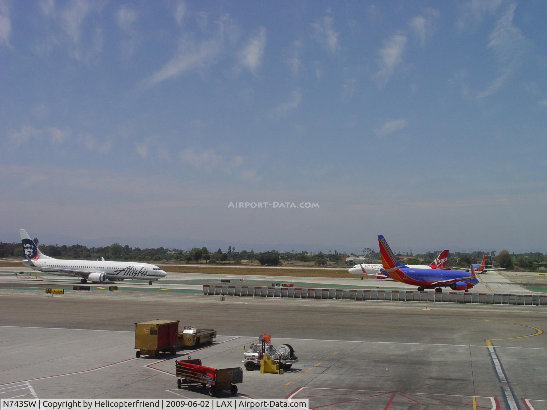N743SW, 1998 Boeing 737-7H4 C/N 29279, Virgin American on 24L, Southwest waiting for it's turn to take off and Alaska Airways still on the taxiway. Another Soutwest is enroute to 24R for take off