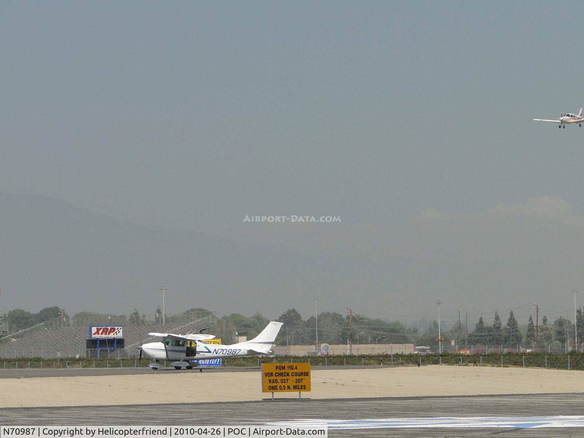 N70987, 1968 Cessna 182L Skylane C/N 18259268, Standing by at runway 26L for landing aircraft. Note large photo opening at rear of the plane with somebody setting there