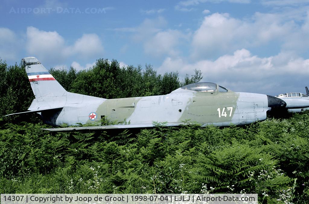 14307, North American IF-86D Sabre C/N Not found 14307, When the Yugoslav civil war broke out, the Serbians left Brnik air base, but left behind this F-86D. In 1998 it was still in place, although nature tried hard to get hold of this storage area.