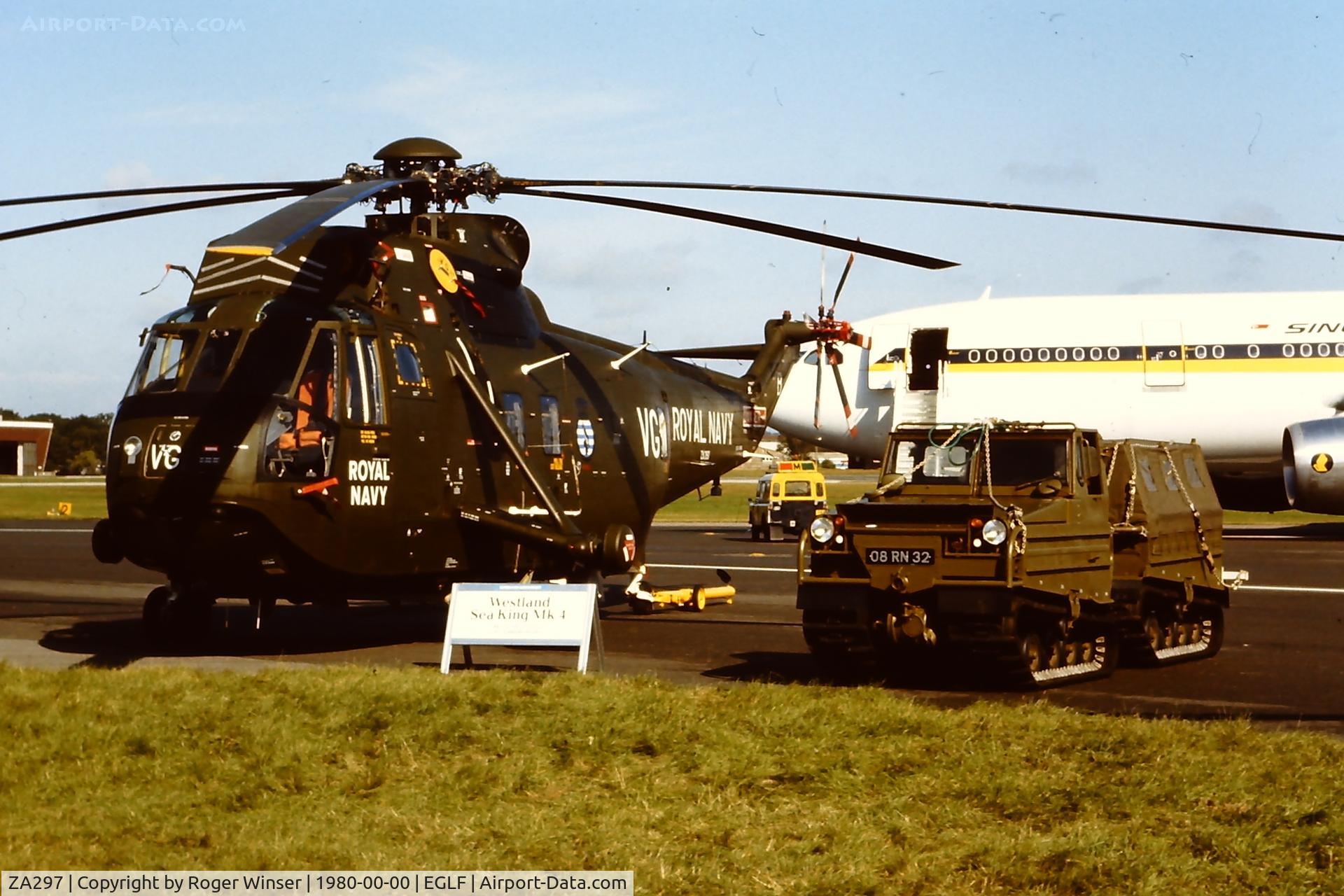 ZA297, 1980 Westland Sea King HC.4 C/N WA911, Royal Navy Sea King helicopter coded VG/B of 846 NAS. Seen at Farnborough in 1980. Scanned from slide, shift of colour (helicopter and Volvo BV202E are painted dark green)