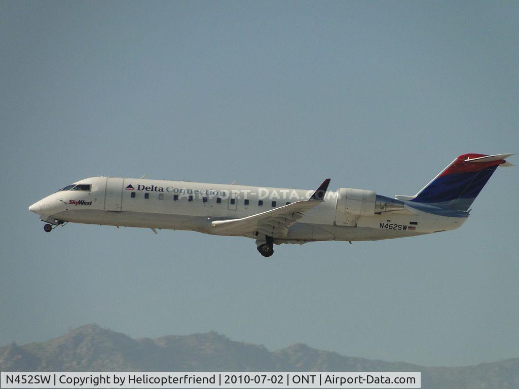 N452SW, 2002 Bombardier CRJ-200ER (CL-600-2B19) C/N 7716, Delta Connection by Sky West with wheels retracting after lift off from runway 26R and heading west