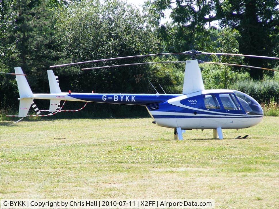 G-BYKK, 1999 Robinson R44 Astro C/N 0572, Robinson R44 being used for ferrying race fans to Silverstone for the British Grand Prix from this temporary heliport a few miles east of Bicester