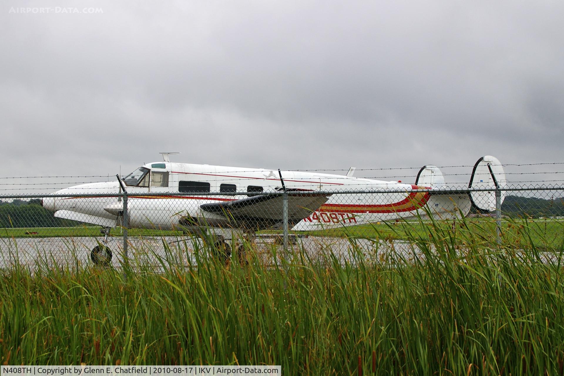 N408TH, 1955 Beech E18S C/N BA-110, Rainy day, seen through the fence