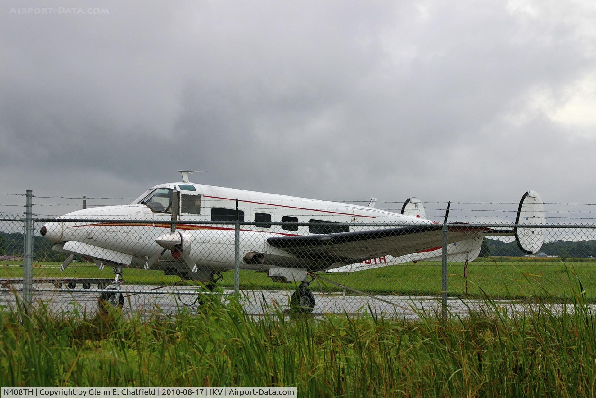 N408TH, 1955 Beech E18S C/N BA-110, Rainy day, seen through the fence