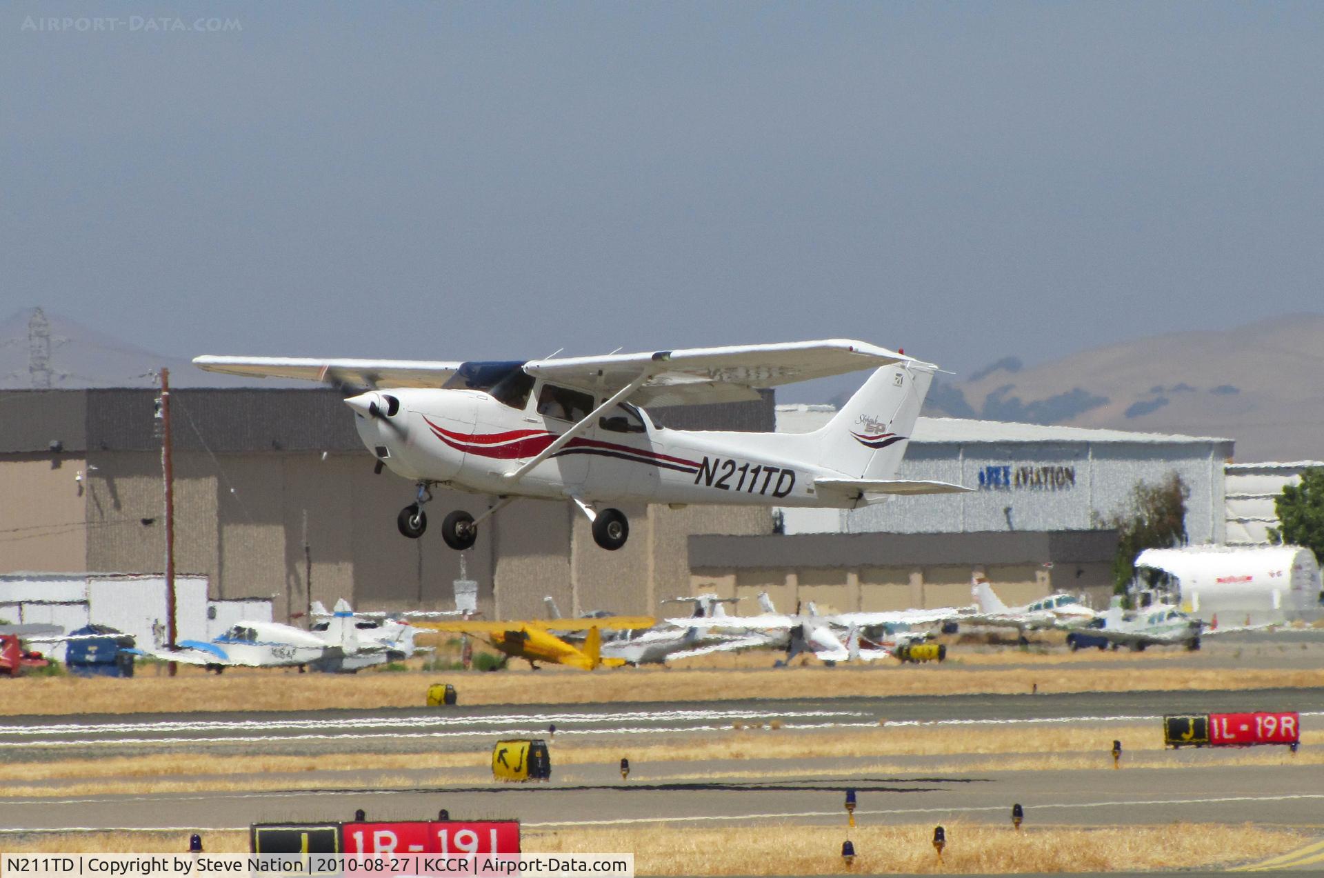 N211TD, 2000 Cessna 172S C/N 172S8524, Locally-based 2000 Cessna 172S climbs out from RWY19L at Buchanan Field with APEX Aviation hangar in background