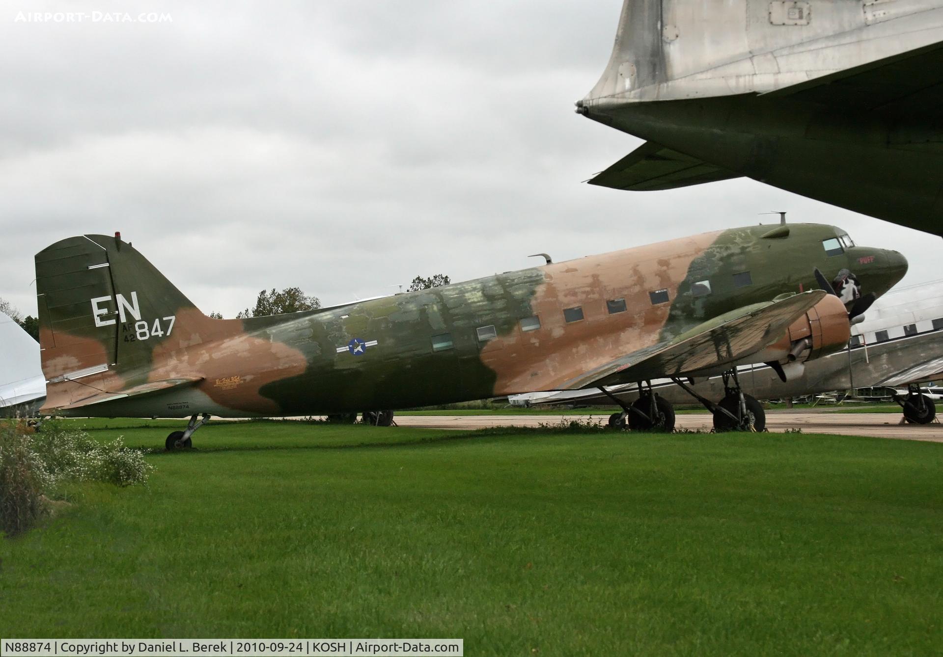 N88874, 1944 Douglas DC3C (C-47A) C/N 12693, A Convairliner's tail frames a fine DC-3 at Basler Turbo Conversions, Oshkosh, WI.